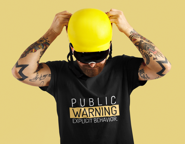 A youg man wearing Black Tshirt with 'Publi Warning, Explicit Behavior' written on it.